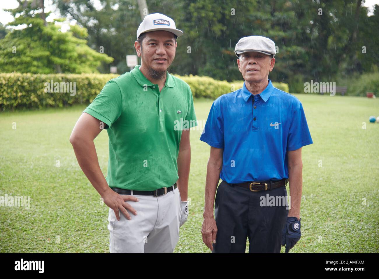 Orgoglioso padre e figlio malese che si posano insieme al campo da golf per prepararsi a giocare Foto Stock