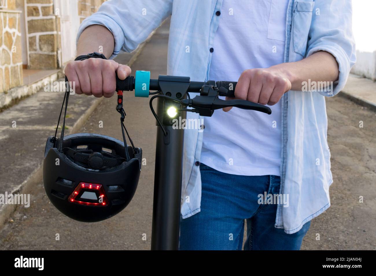 Immagine ritagliata di un giovane uomo con il suo scooter elettrico e la cassa appesa al polso Foto Stock