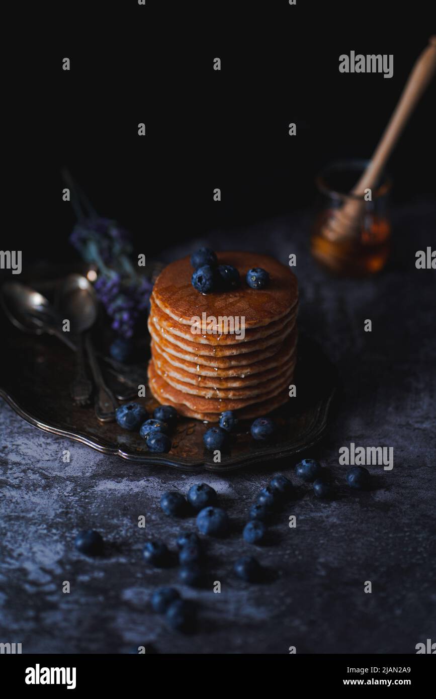 Pancake con mirtilli e miele in stile fotografico dark food Foto Stock