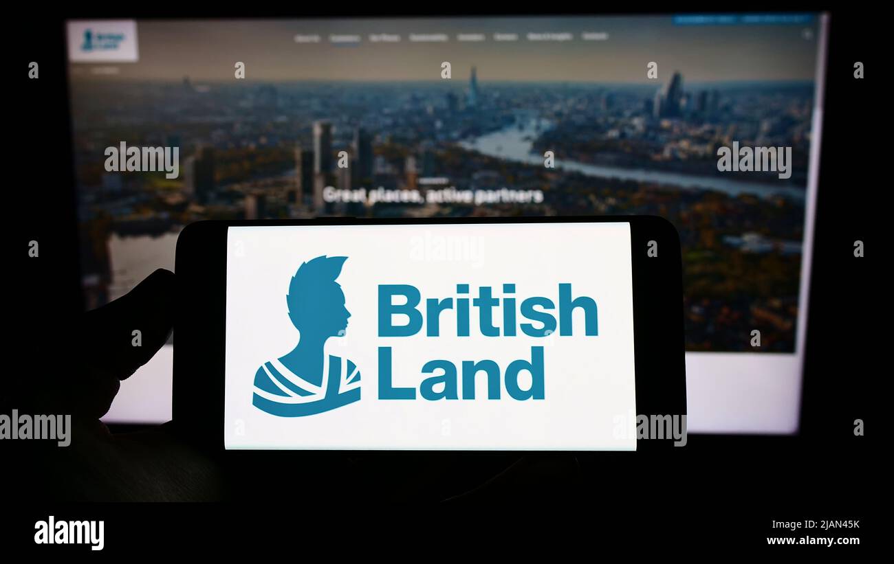 Persona che tiene il cellulare con il logo della società The British Land Company plc sullo schermo di fronte al sito web aziendale. Mettere a fuoco sul display del telefono. Foto Stock