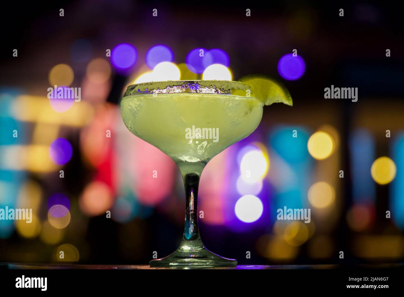Cocktail margarita con una fetta di limone. Cocktail in primo piano sullo sfondo delle colorate luci notturne, del club Foto Stock