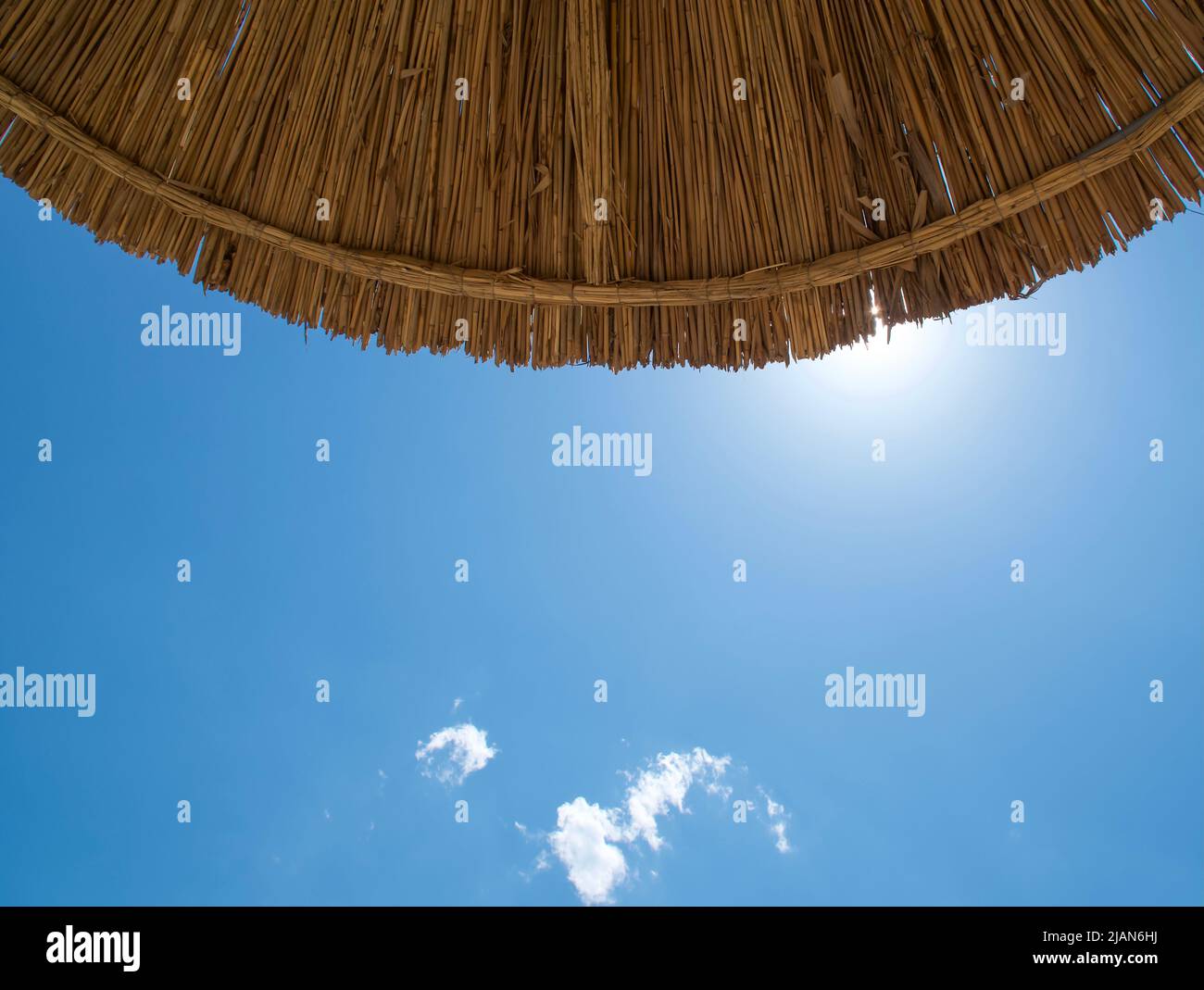 Ombrello spiaggia contro il cielo blu sulla spiaggia. Vista dal basso, estate Foto Stock