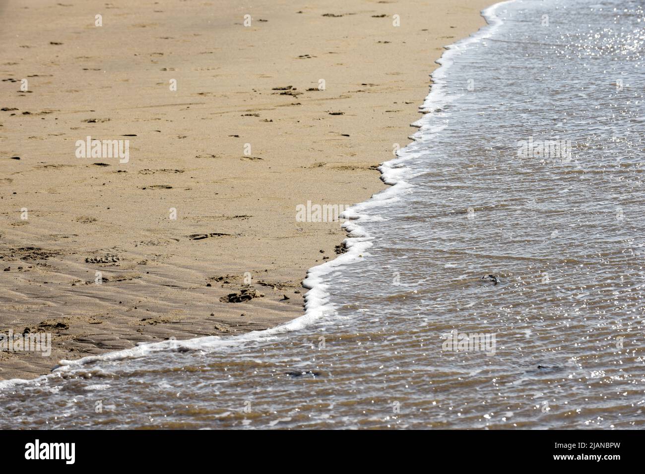 Spiaggia di mare con acqua dell'oceano che lambiscono la spiaggia di sabbia Foto Stock