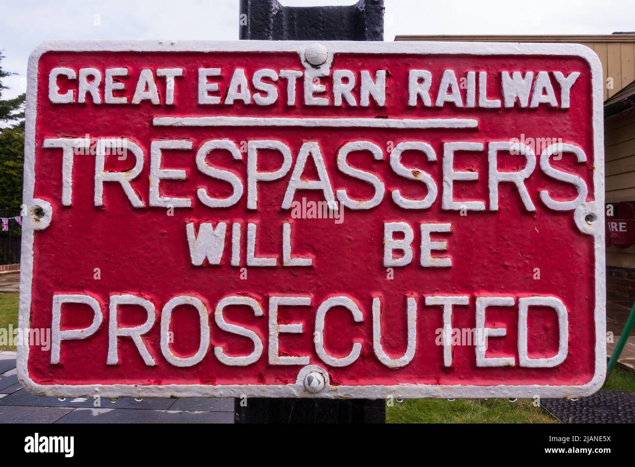 Grande ferrovia orientale, Trespassers sarà perseguitato segno di ghisa in rosso con lettere bianche. Stazione di Bannold, Fen Drayton, Cambridgeshire. Foto Stock