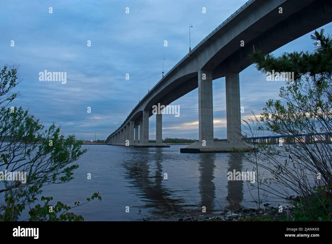 Victory Bridge sul fiume Raritan a Perth Amboy, New Jersey, in una nuvolosa giornata primaverile al tramonto, con i supporti del ponte riflessi nell'acqua -06 Foto Stock