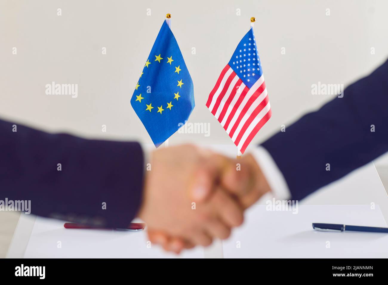 Piccole bandiere di Stati Uniti e Unione europea durante la stretta di mano che testimonia il successo dell'accordo. Foto Stock