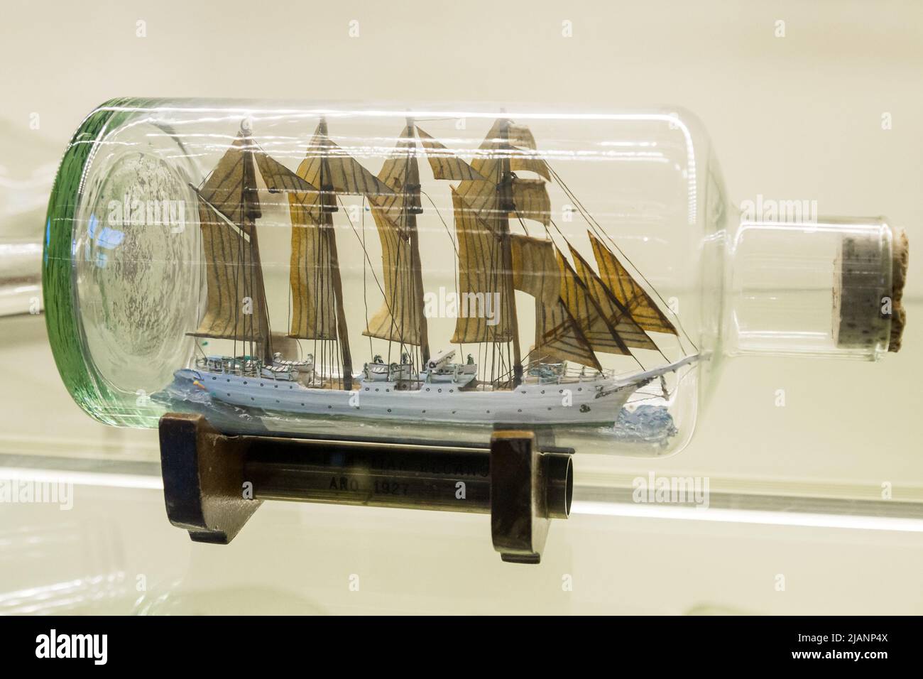 Istanbul, Turchia, 23 marzo 2019: Nave alta in miniatura con vele rigate in una bottiglia di vetro trasparente esposta su un piccolo stand di legno su un bianco Foto Stock
