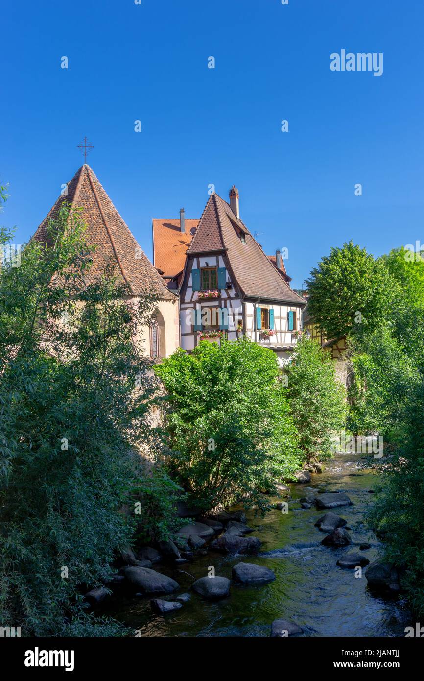 Kaysersberg, Francia - 30 maggio 2022: Case storiche a graticcio sul fiume Weiss nel centro del villaggio di Kaysersberg Foto Stock