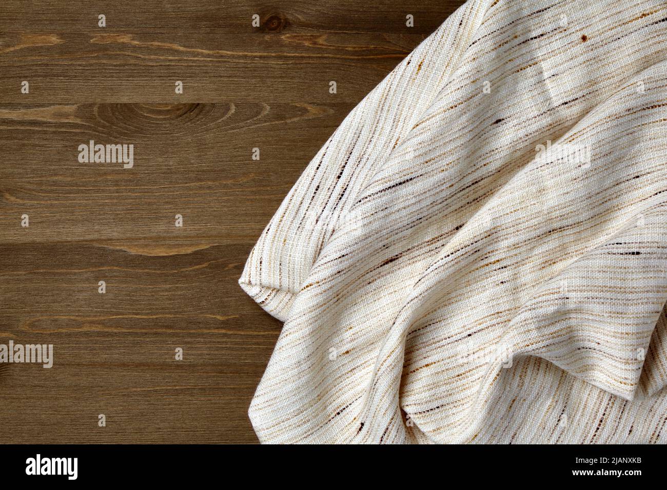 Tovaglia di lino grossolano chiaro e sbriciolato su un tavolo grunge di legno scuro Foto Stock