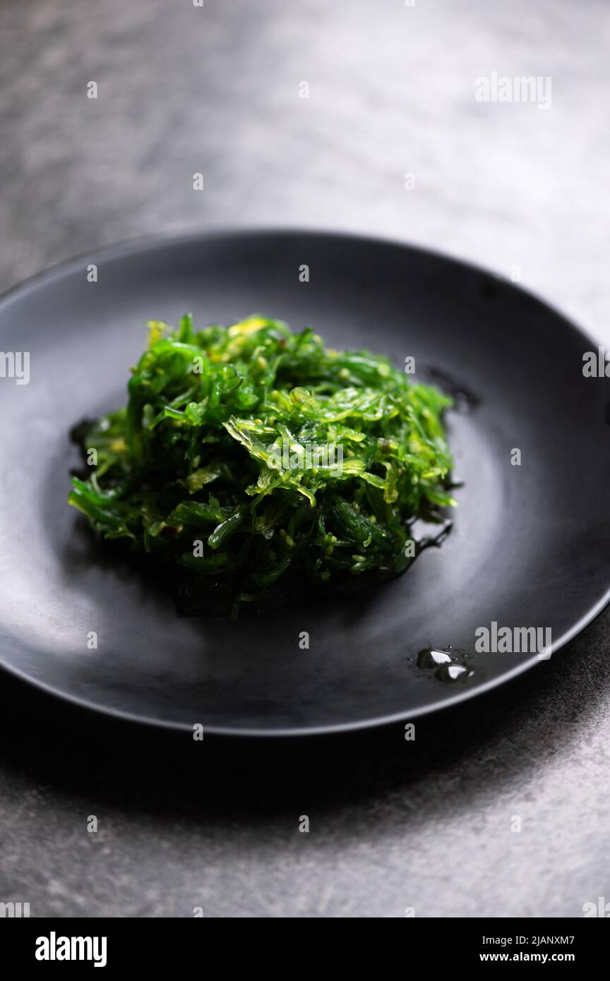 Insalata di alghe in piatto nero Foto Stock
