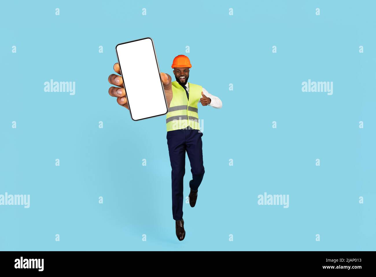 Ottima scelta. Excited Black Builder saltare con smartphone vuoto a portata di mano Foto Stock