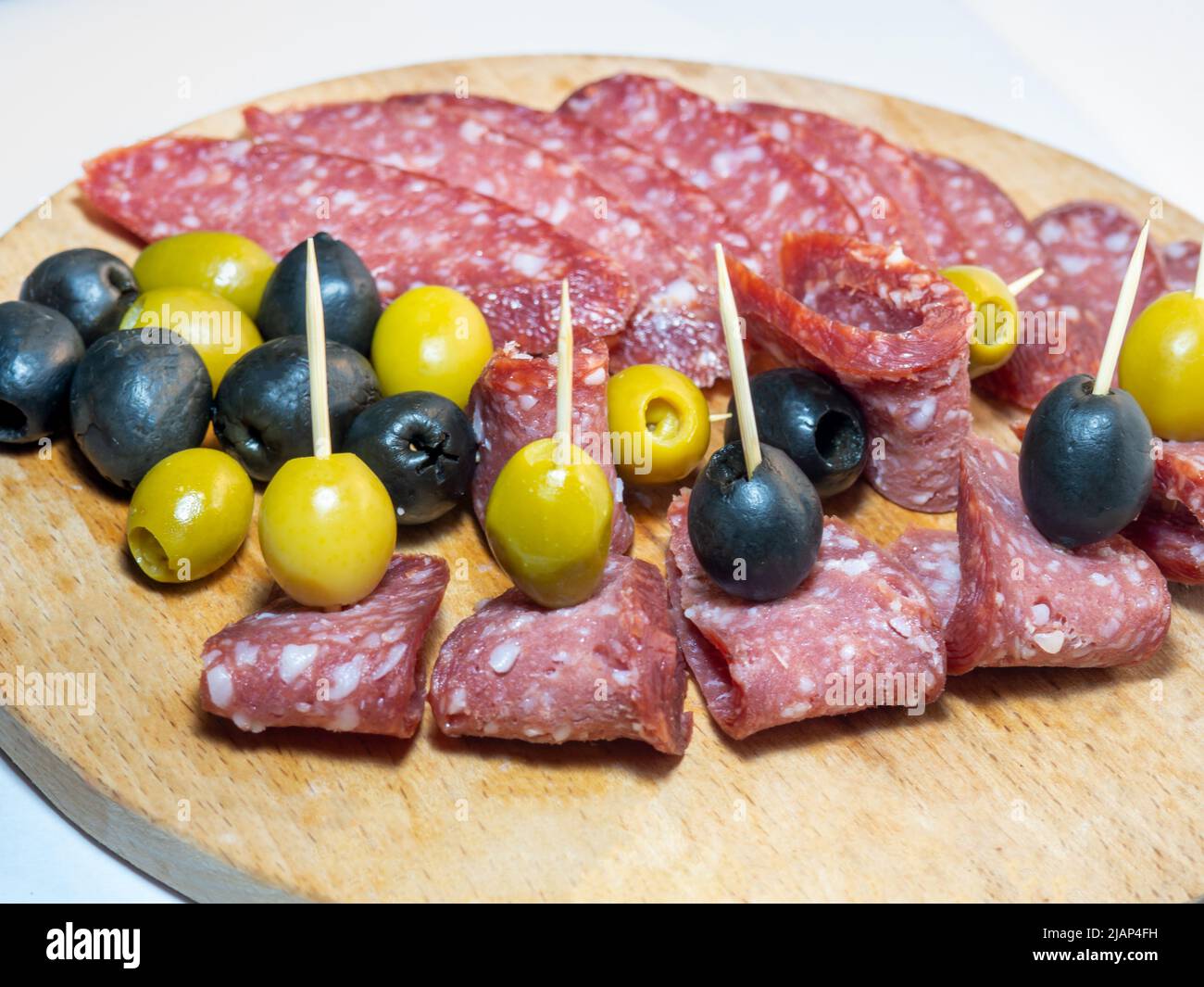 Affettare salame e olive su stuzzicadenti. Affettare su un tavolo da cucina  Foto stock - Alamy