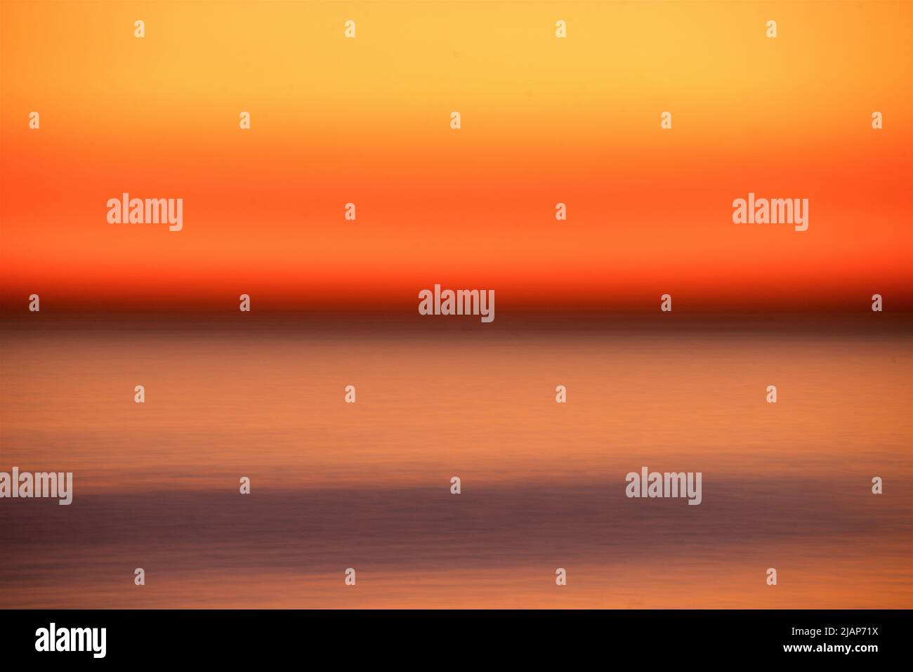 Dettaglio astratto del mare sfocato dal movimento con cielo di crepuscolo arancione sopra l'orizzonte scuro. Canale inglese, Regno Unito. Foto Stock