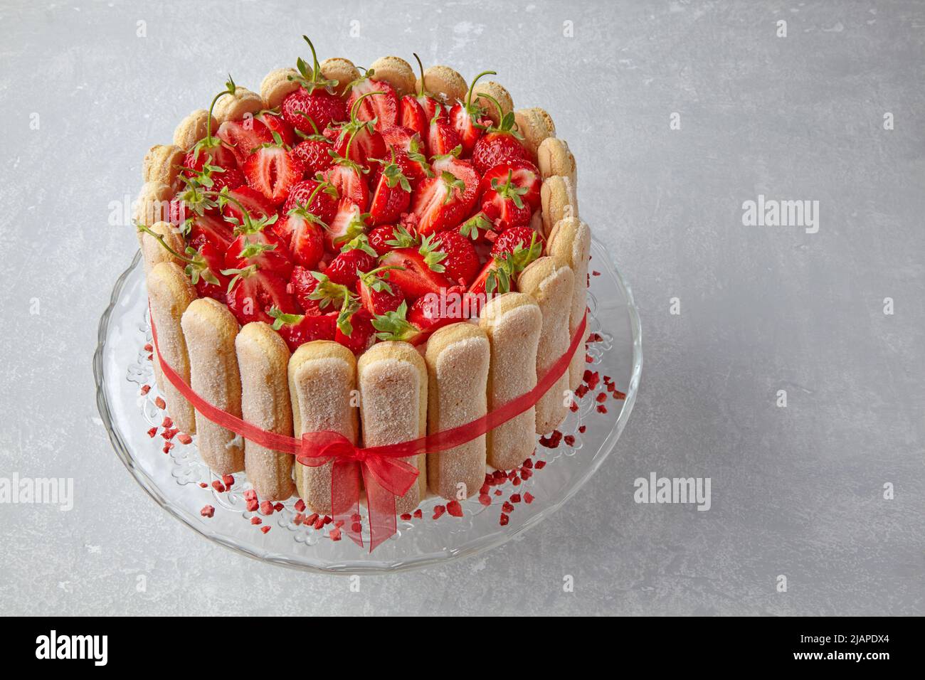Torta con fragole, biscotti savoiardi e mascarpone legati con un nastro rosso Foto Stock