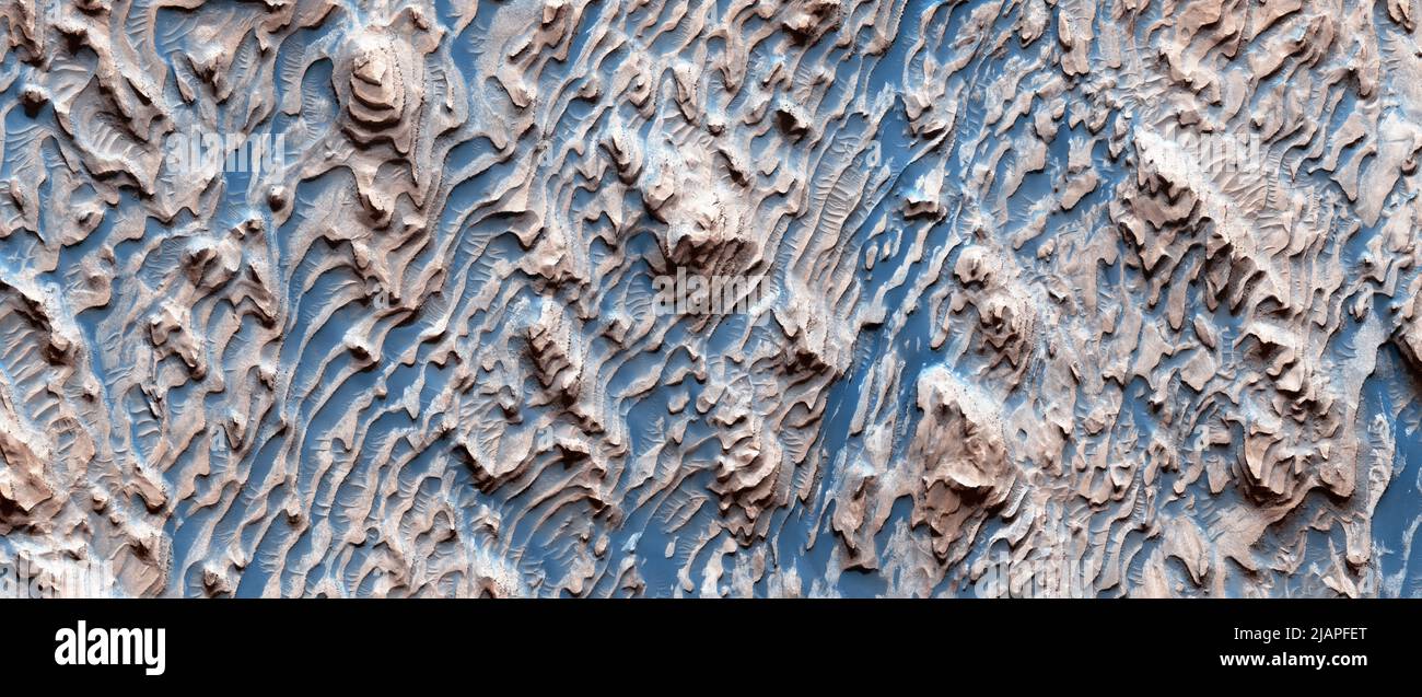 Terreno marziano. Questa immagine mostra un classico esempio di roccia sedimentaria marziana nel cratere Danielson. I molti strati di roccia sono regolarmente distanziati, formando passi; questo implica una serie di strati di cappuccio forti alternati con strati più deboli. Su piccola scala, gran parte della roccia è fortemente fratturata. Poiché i pezzi fratturati si adattano perfettamente insieme, questo si è verificato dopo che il deposito si è trasformato in roccia. MARS immagine a colori migliorata ( meno di 1 km (sotto un miglio) dall'alto verso il basso) Ê una versione ottimizzata e migliorata delle immagini NASA. Credit: NASA/JPL/UArizona Foto Stock