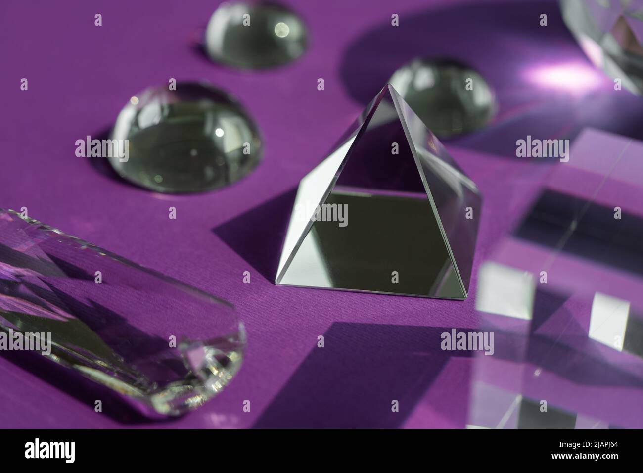 Luce rifrangente a prisma di cristallo, cristalli magici e piramide, sfera e cubo su sfondo viola. Pratica di cristallo di guarigione spirituale. Feng Shui, bravo Foto Stock