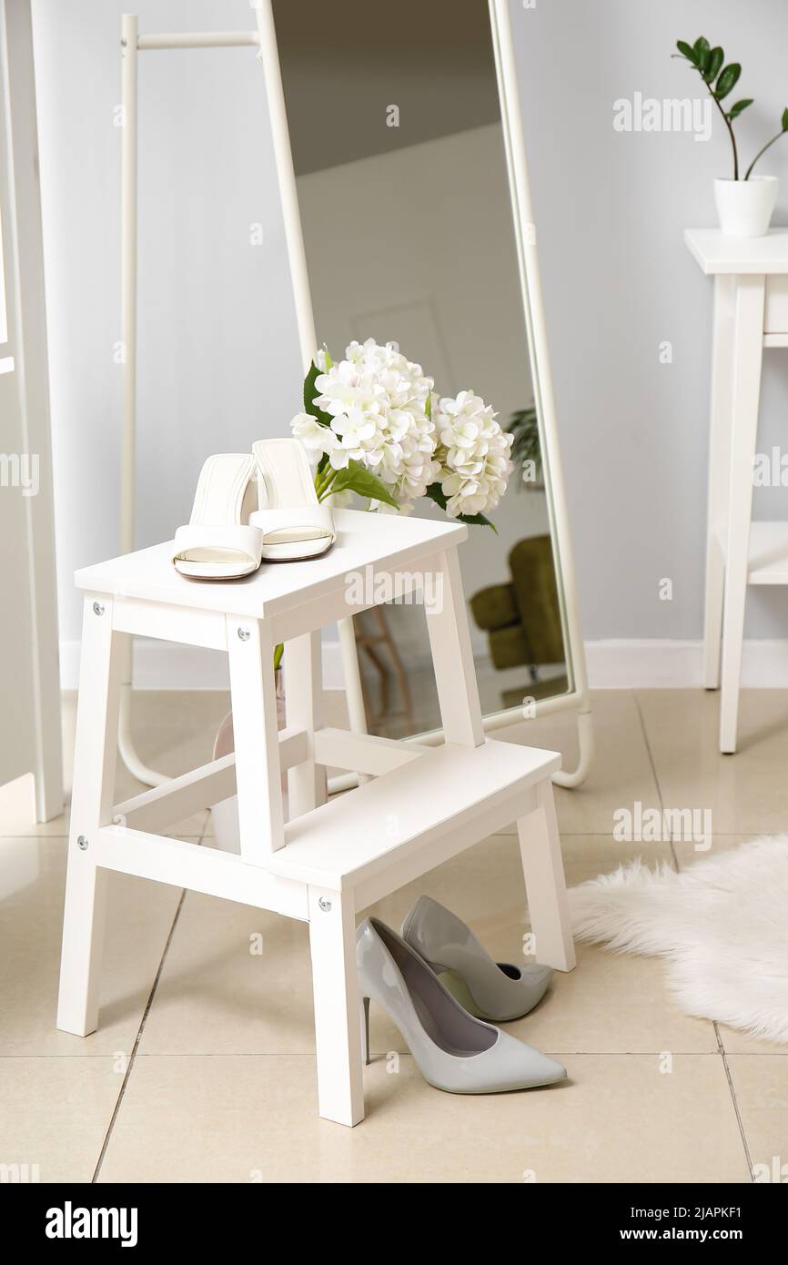 Scala a gradini con scarpe eleganti e bellissimi fiori in camera Foto Stock