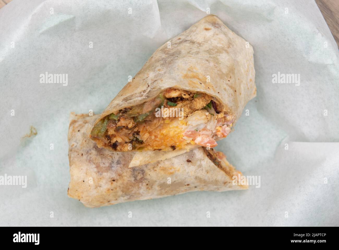 Vista dall'alto del burrito di chorizo di maiale caricato tagliato in metà tutta la carne, il formaggio, i fagioli e il riso serviti in un cestino di fast food. Foto Stock