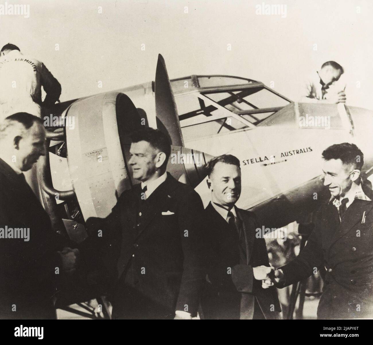 Charles Ulm e J. L. Skilling sono stati salutati di fronte a Stella Australis Plane VH-UXY da funzionari americani, Oakland Aerodrome, California, Stati Uniti ca. 1934 Foto Stock