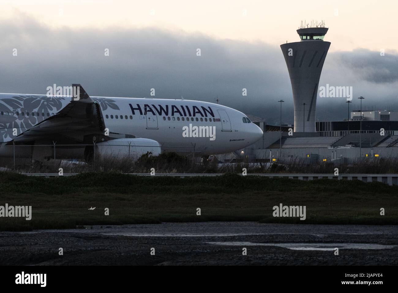 Un aereo hawaiano delle compagnie aeree di fronte alla torre di controllo del traffico dell'aeroporto internazionale di San Francisco a Millbrae, California, USA. Foto Stock