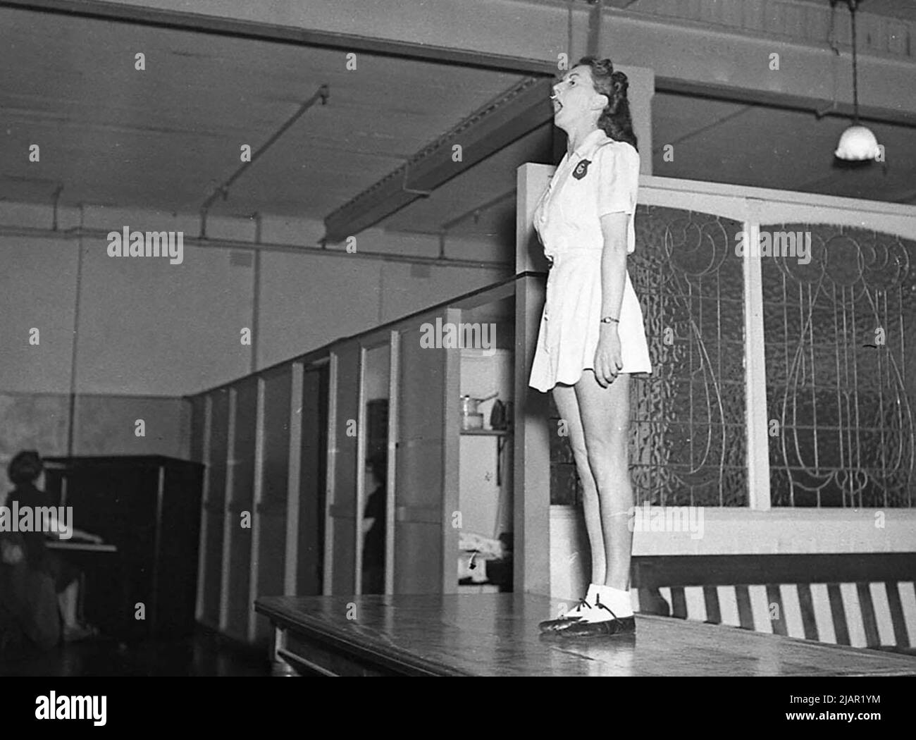 Donna in piedi su un tavolo cantando, accompagnato da un pianista Miss Mellor ca 1947 Foto Stock