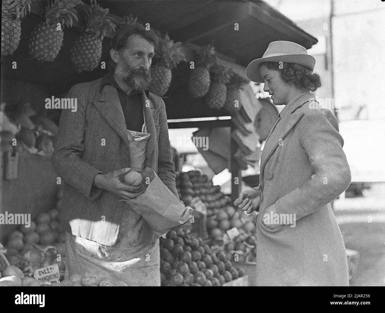 Donna che acquista frutta da un venditore per le strade di Sydney Australia - uomo che vende frutta da un frutteto ca. 1940 Foto Stock