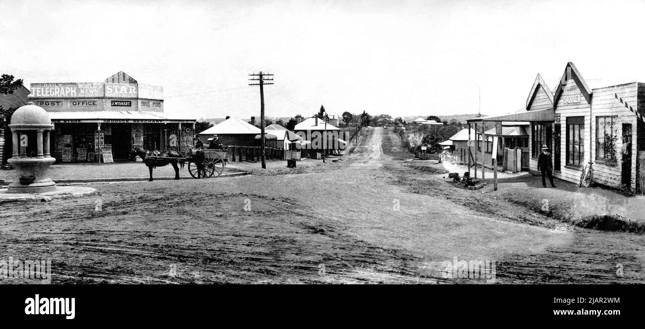 Guardando verso nord lungo Pennant Hills Road dall'angolo di Church Street (ora Marsden Road) e Pennant Hills Road, Carlingford, c.1912. Fontana da bere a sinistra (installato 1911 e rimosso 1929). Ufficio postale e negozio generale J. Wishart titolare. Pennant Hills Wireless Telegraph Station in lontananza a destra (aperto 1912). William Sullivan Saddler (forse i suoi figli che giocano in grondaia). Sullivan ha rinnovato la sua sede ad una finitura di mattone in 1915 - qui visto in resistenza. CA. 1912 Foto Stock