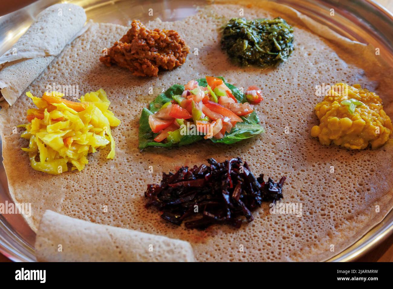 Injera servito con verdure e lenticchie. L'injera, il cibo di base dell'Etiopia, è un pane piatto di pasta madre fatto dalla farina di teff. Foto Stock