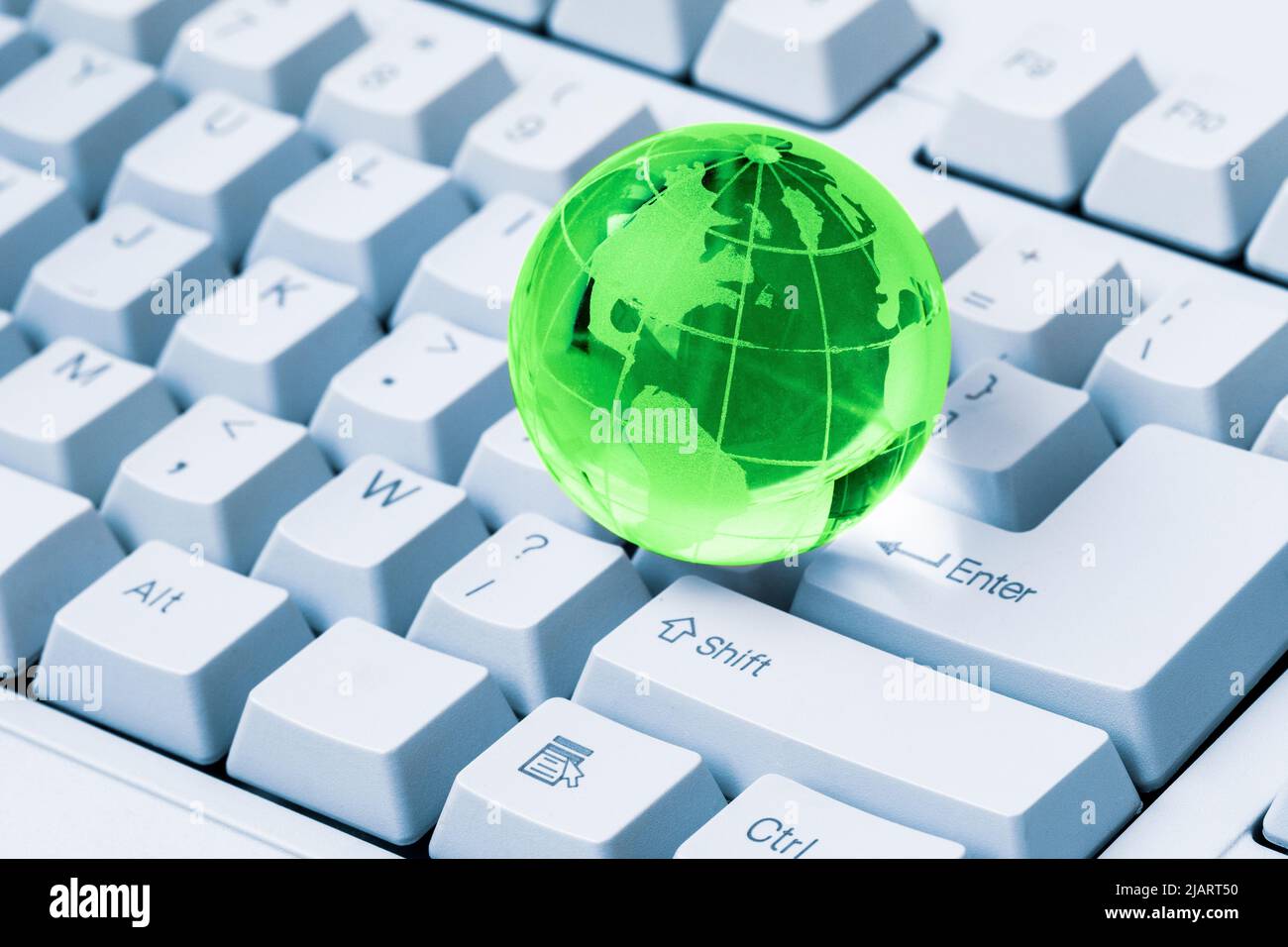 Globo di cristallo verde della Terra su una tastiera del computer. Concetto di business globale e internazionale. Connessione a tutto il mondo. Concetto di social network. Foto Stock