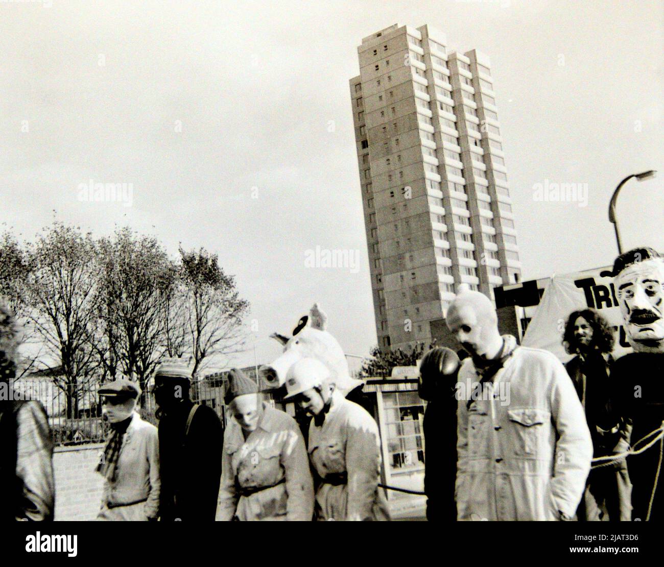 I manifestanti, tra cui alcune maschere o maschere per la testa, partecipano a una manifestazione antirazzista a Leicester, Inghilterra, Regno Unito, Isole britanniche, nel 1972. Blocco torre sullo sfondo. Foto Stock