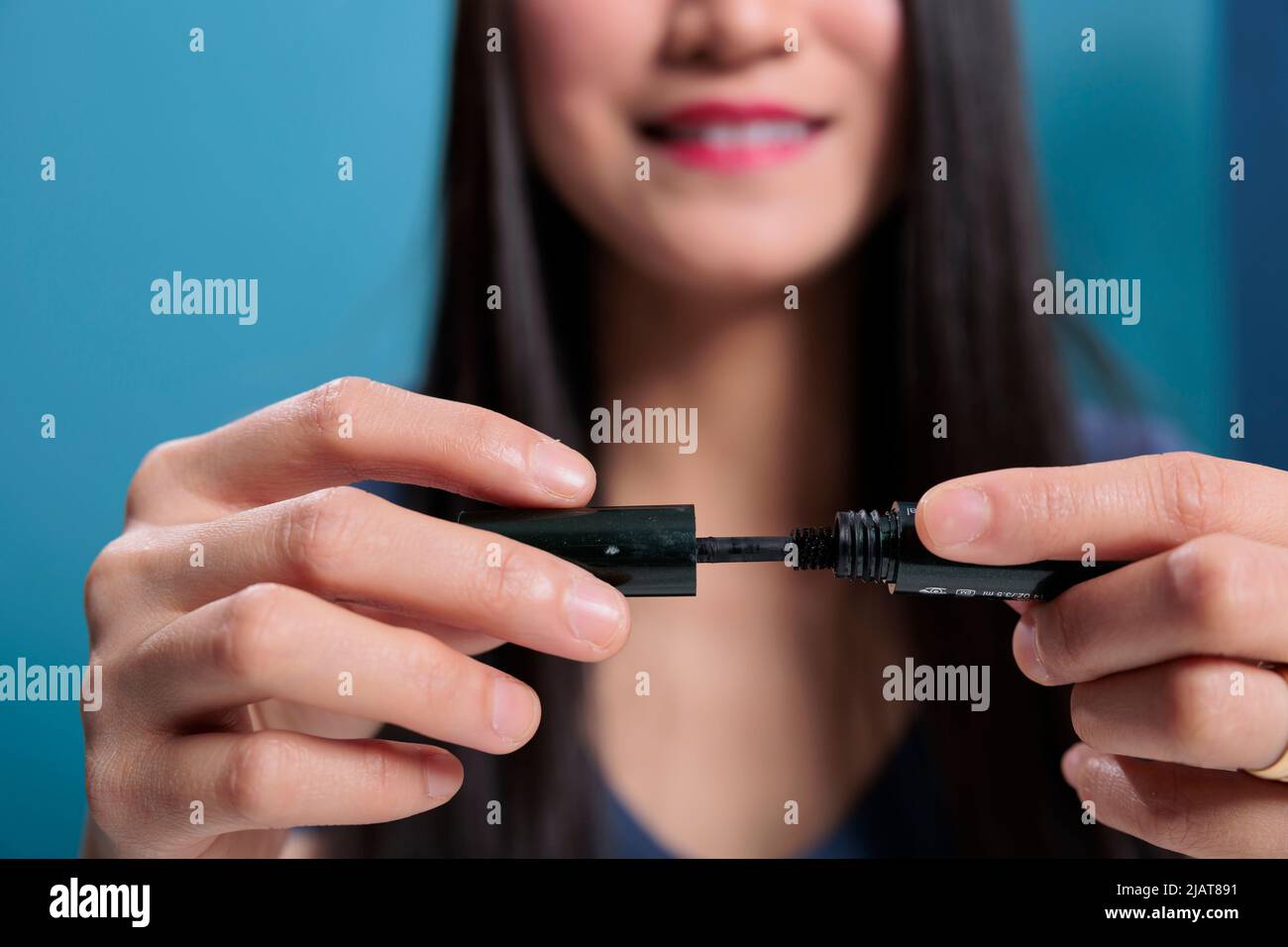 Il guru asiatico di bellezza mostra il mascara nero alla macchina fotografica che fa pubblicità al prodotto cosmetico che filma il video tutorial per il canale di vlogging. Recensione della registrazione dei social media influencer. Primo piano Foto Stock