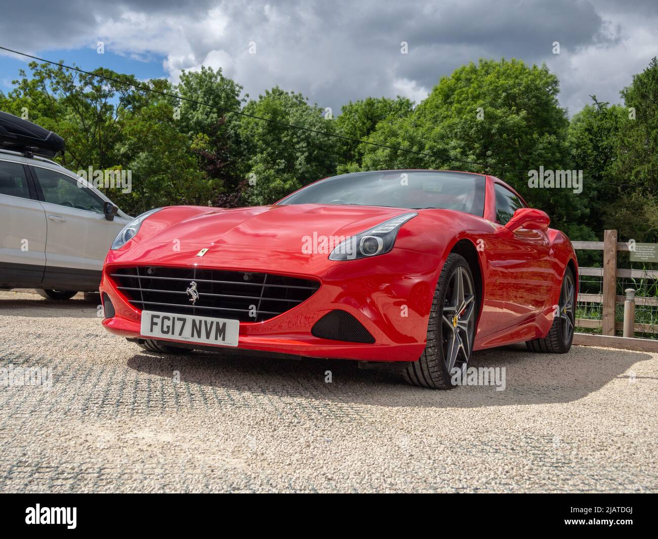 Basso punto di vista girato di una Ferrari rossa auto sportiva parcheggiata nel villaggio di Castle Ashby, Northamptonshire, Regno Unito Foto Stock