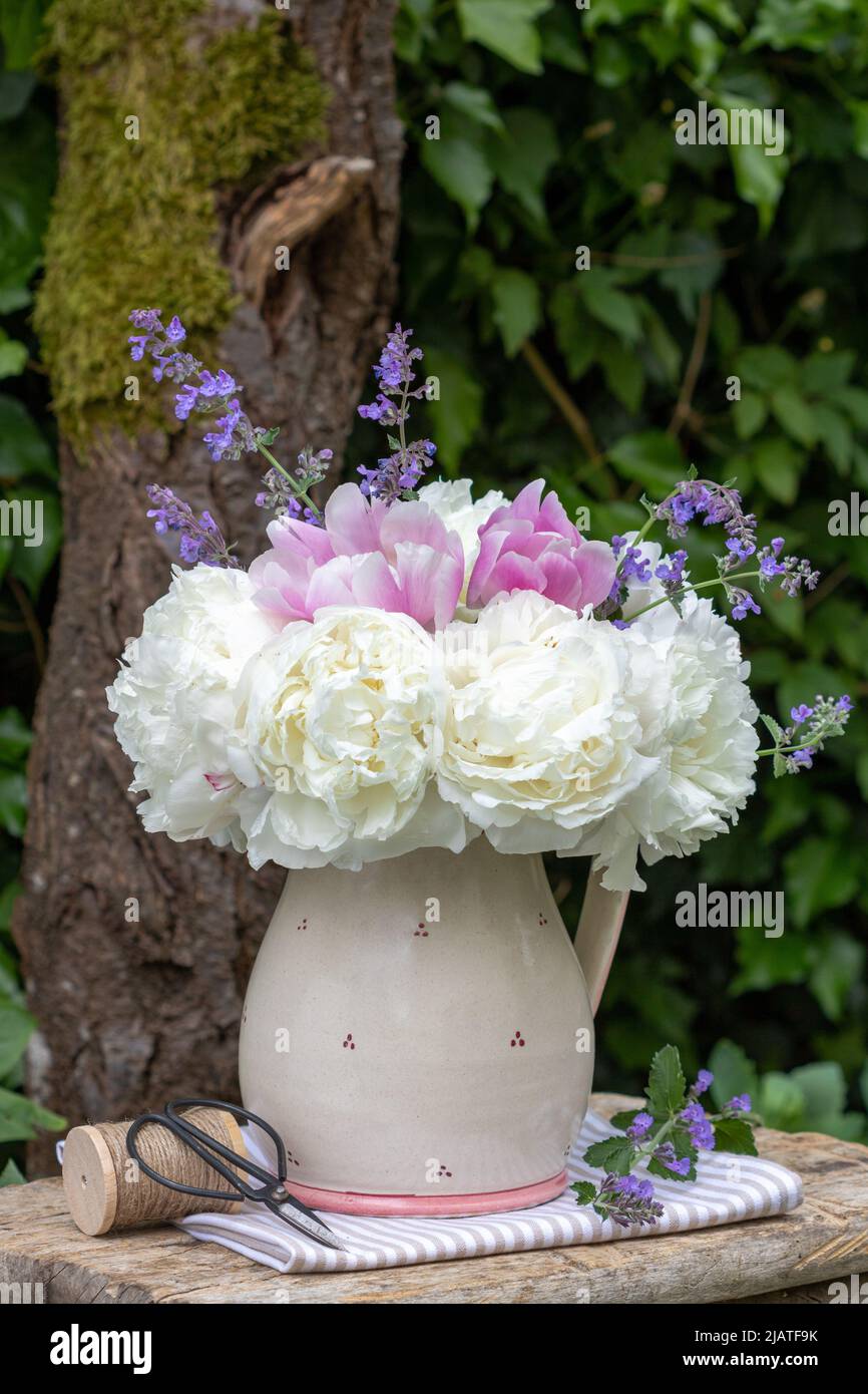 bouquet di fiori di peonia bianchi e rosa in vaso rustico in giardino Foto Stock