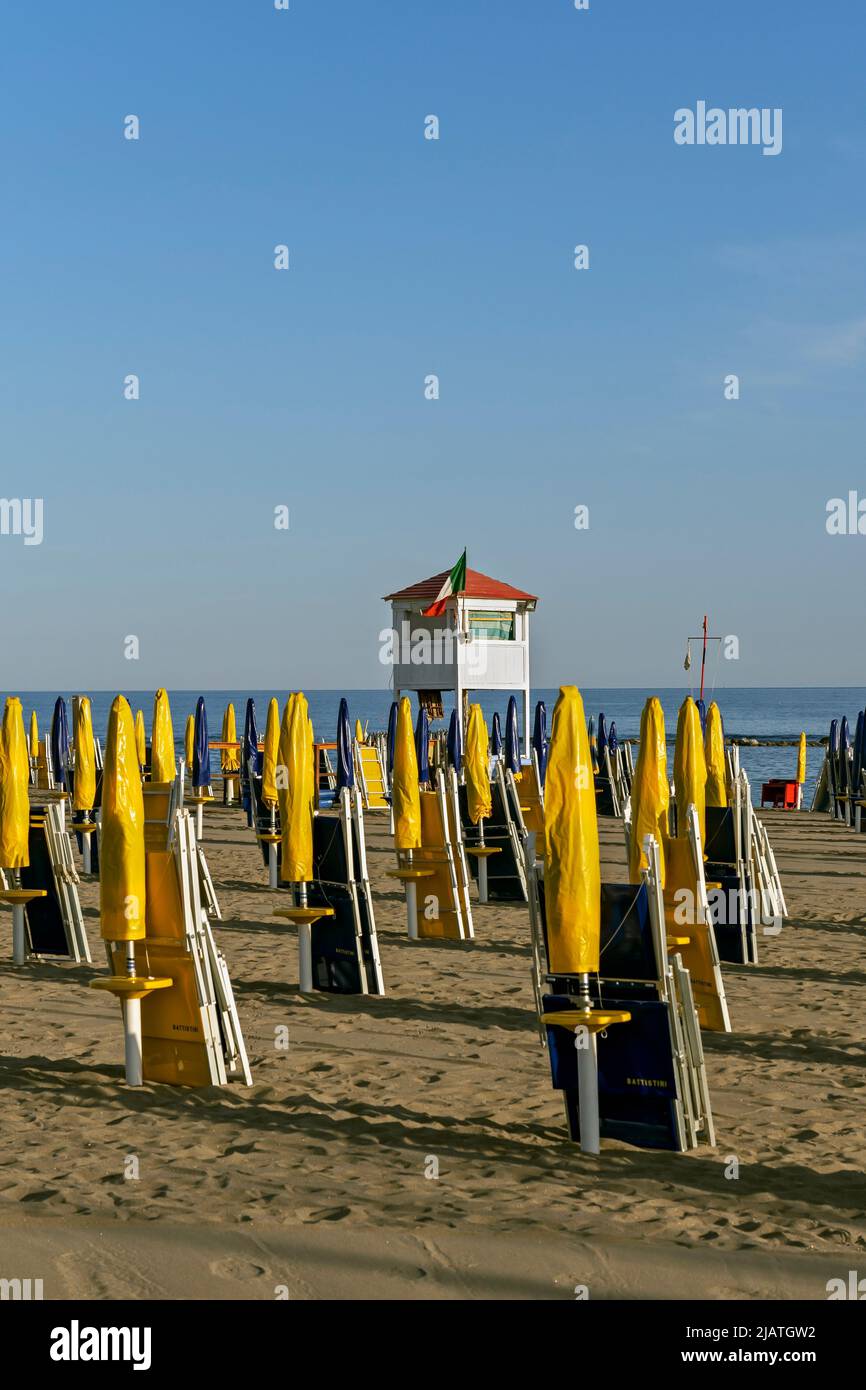 Torre del bagnino e linee di ombrelloni e sdraio giallo e blu scuro sulla spiaggia di Ostia, Roma, Italia, Europa, Unione europea, UE Foto Stock