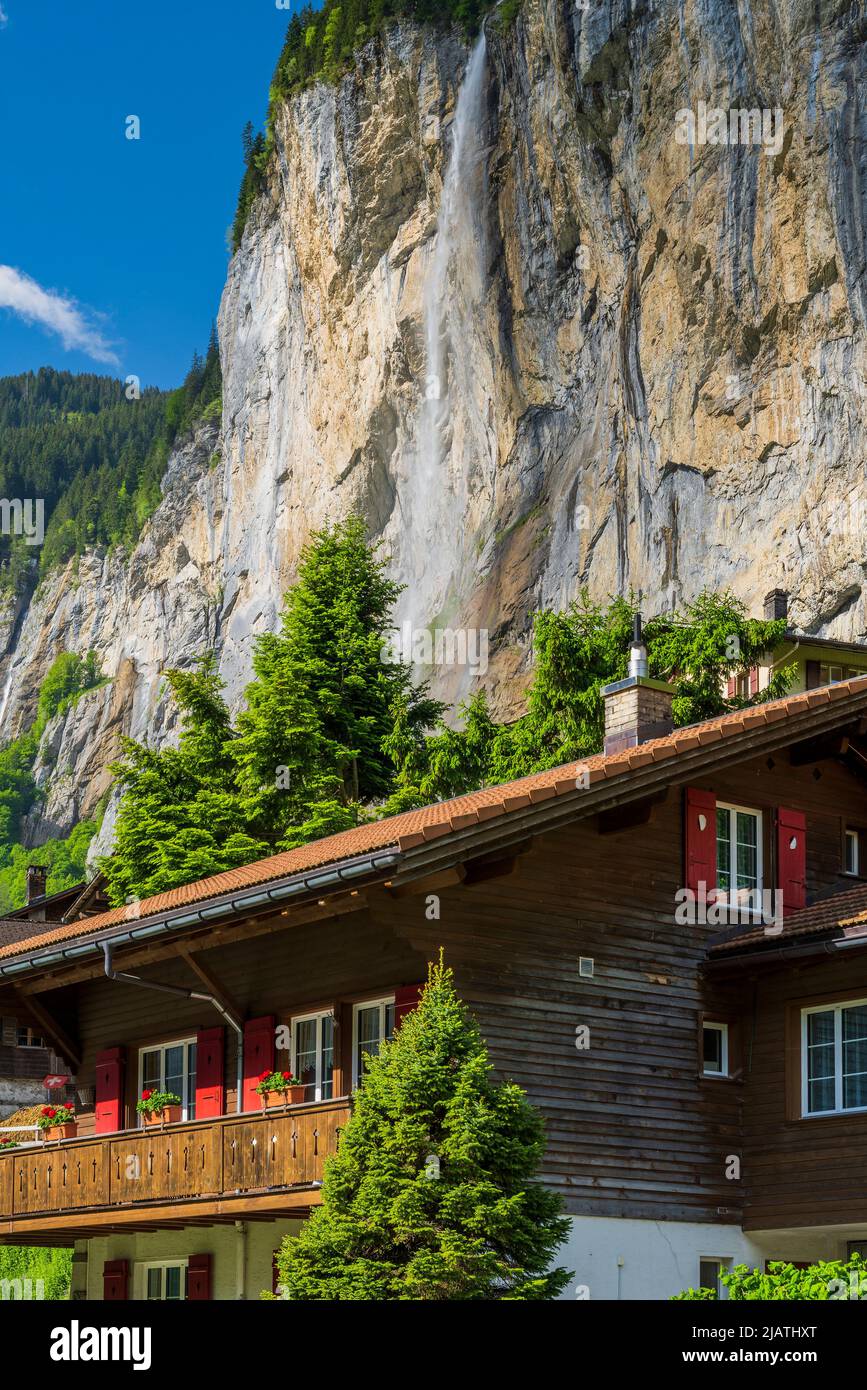 Tipica casa di montagna svizzera con cascata Staubbach, Lauterbrunnen, Cantone di Berna, Svizzera Foto Stock