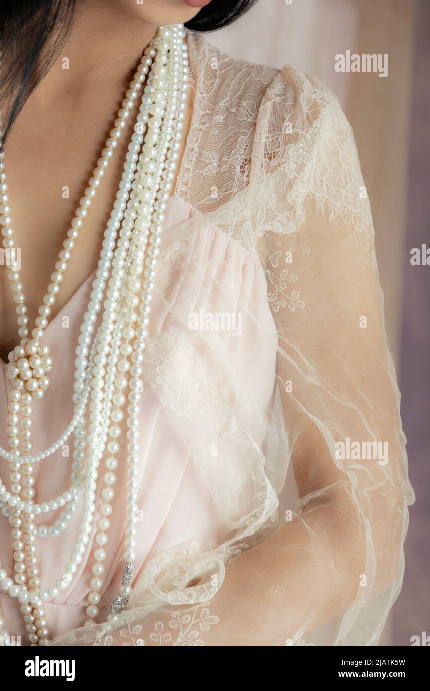 Una bella donna asiatica che indossa un vestito rosa vintage e posa in posa tra il tessuto velato drappeggiato Foto Stock
