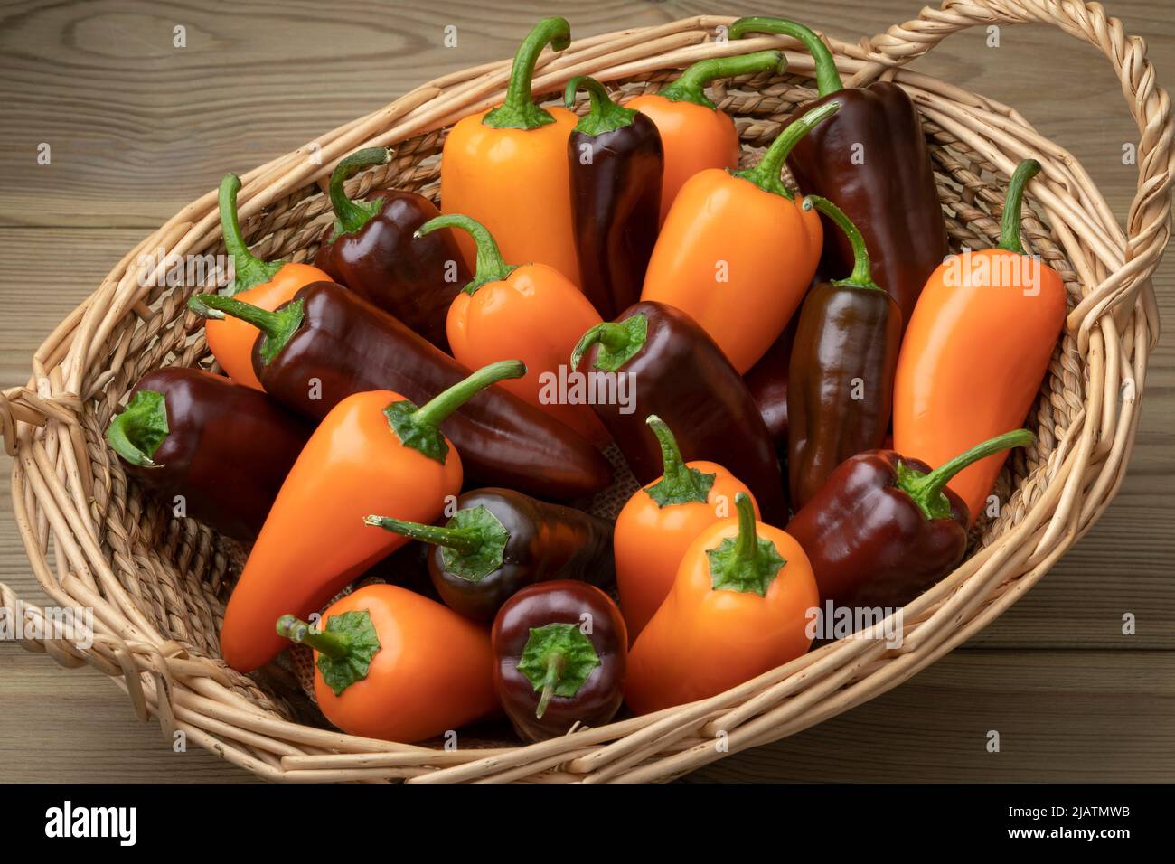 Cestino con arancia fresca intera e mini peperoni a punta al cioccolato da vicino su sfondo di legno Foto Stock