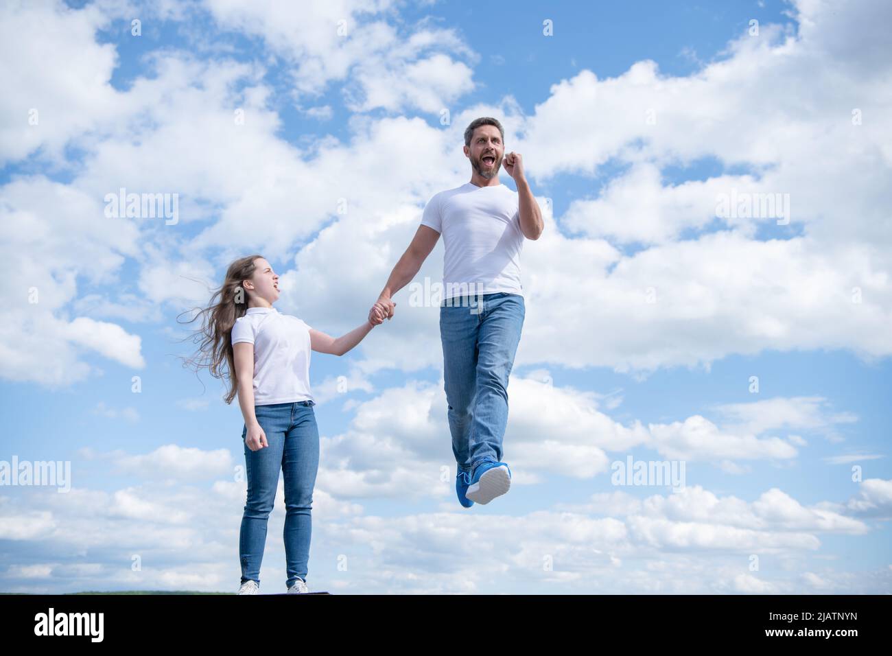 la figlia tiene suo padre ispirato che salta in cielo Foto Stock