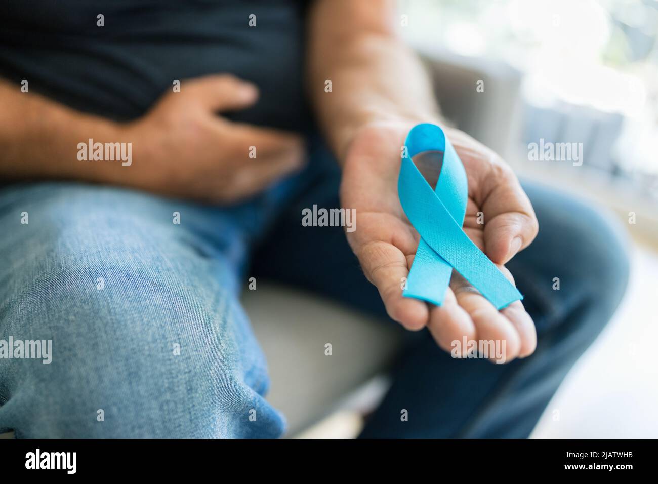 Uomo anziano che tiene un nastro blu di consapevolezza del cancro in mano Foto Stock