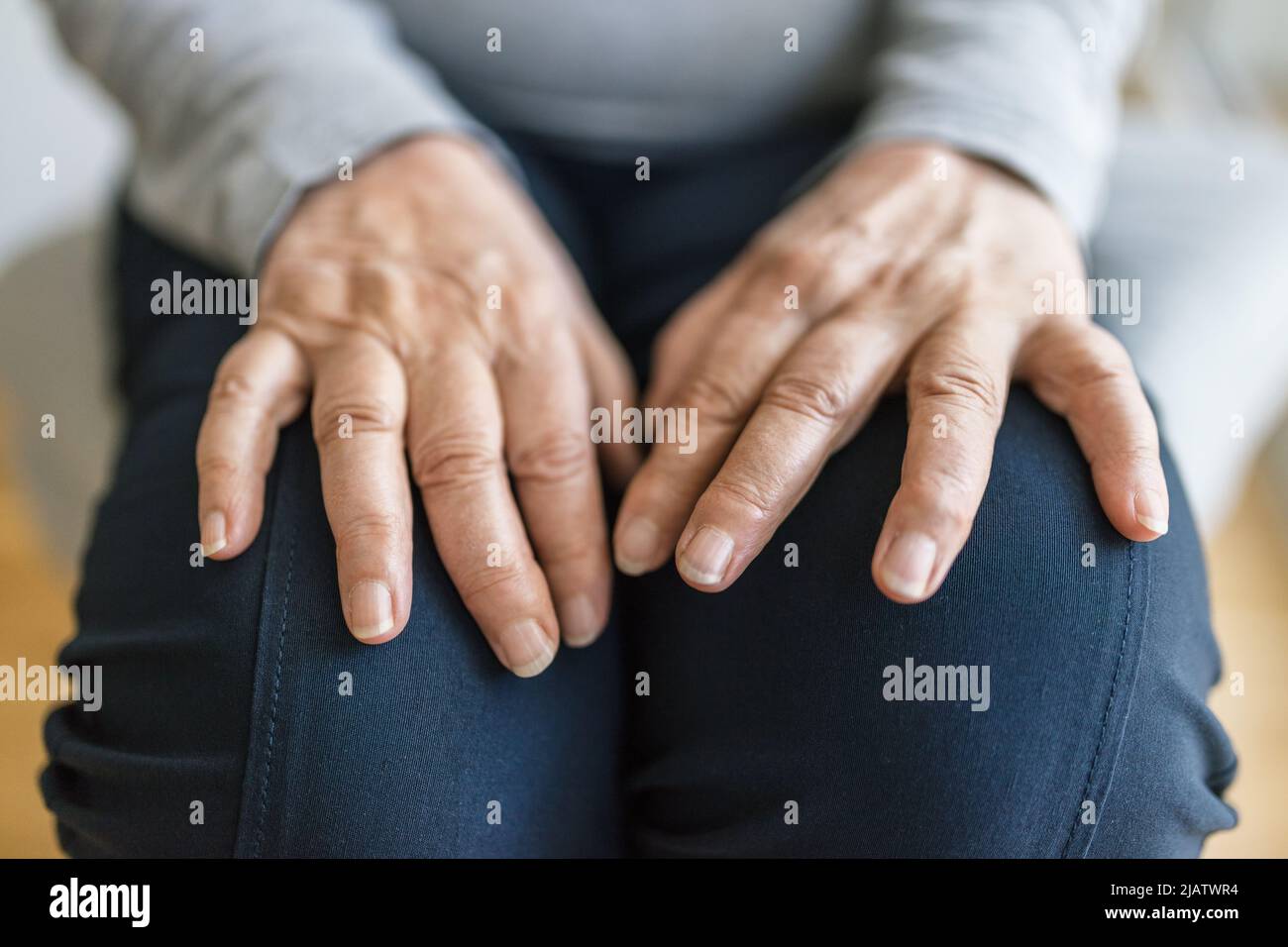Donna anziana a casa che soffre di artrite Foto Stock