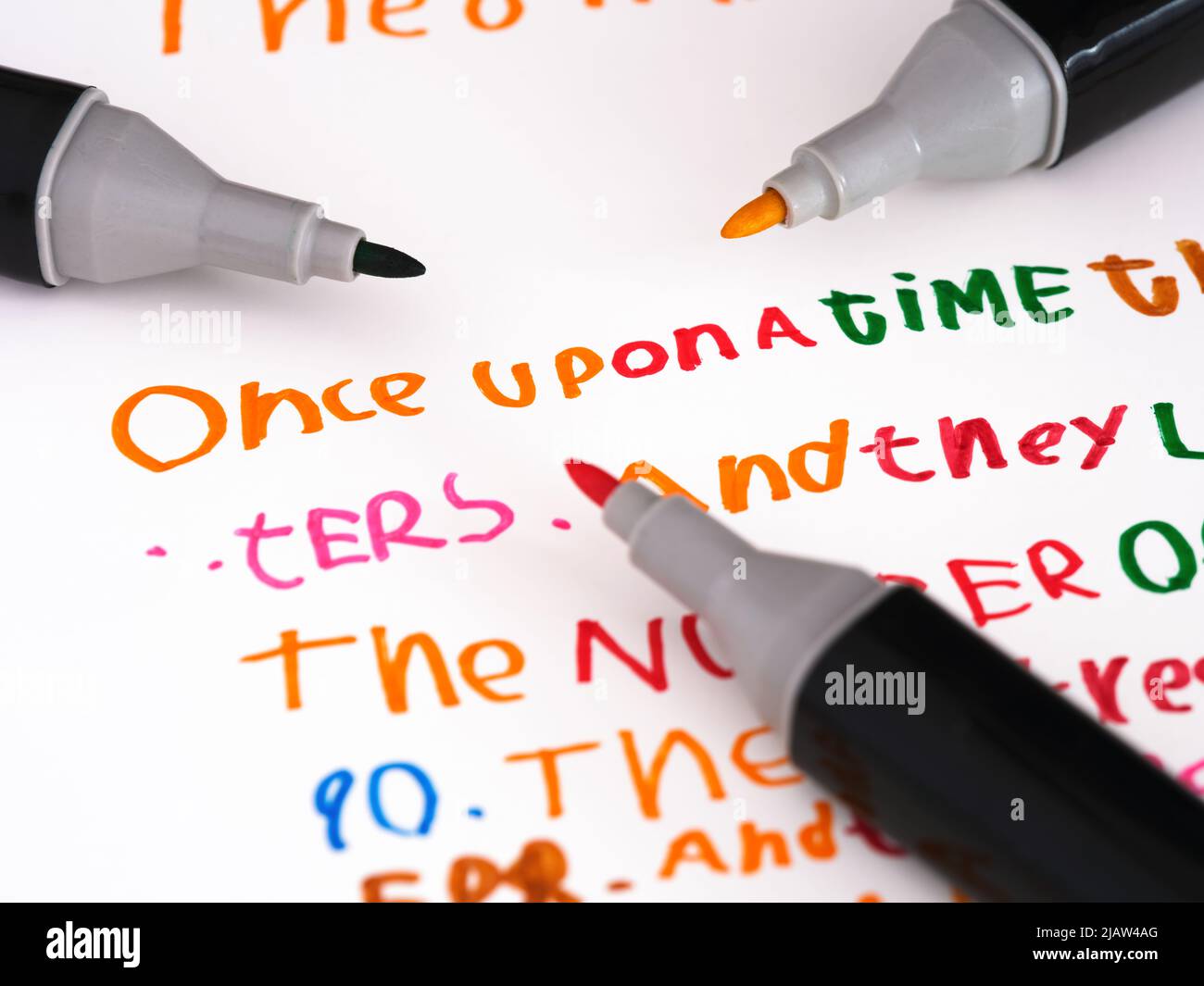 Tre marcatori che posano su un pezzo di carta con una storia che è in una scrittura a mano dei bambini una volta... Foto Stock