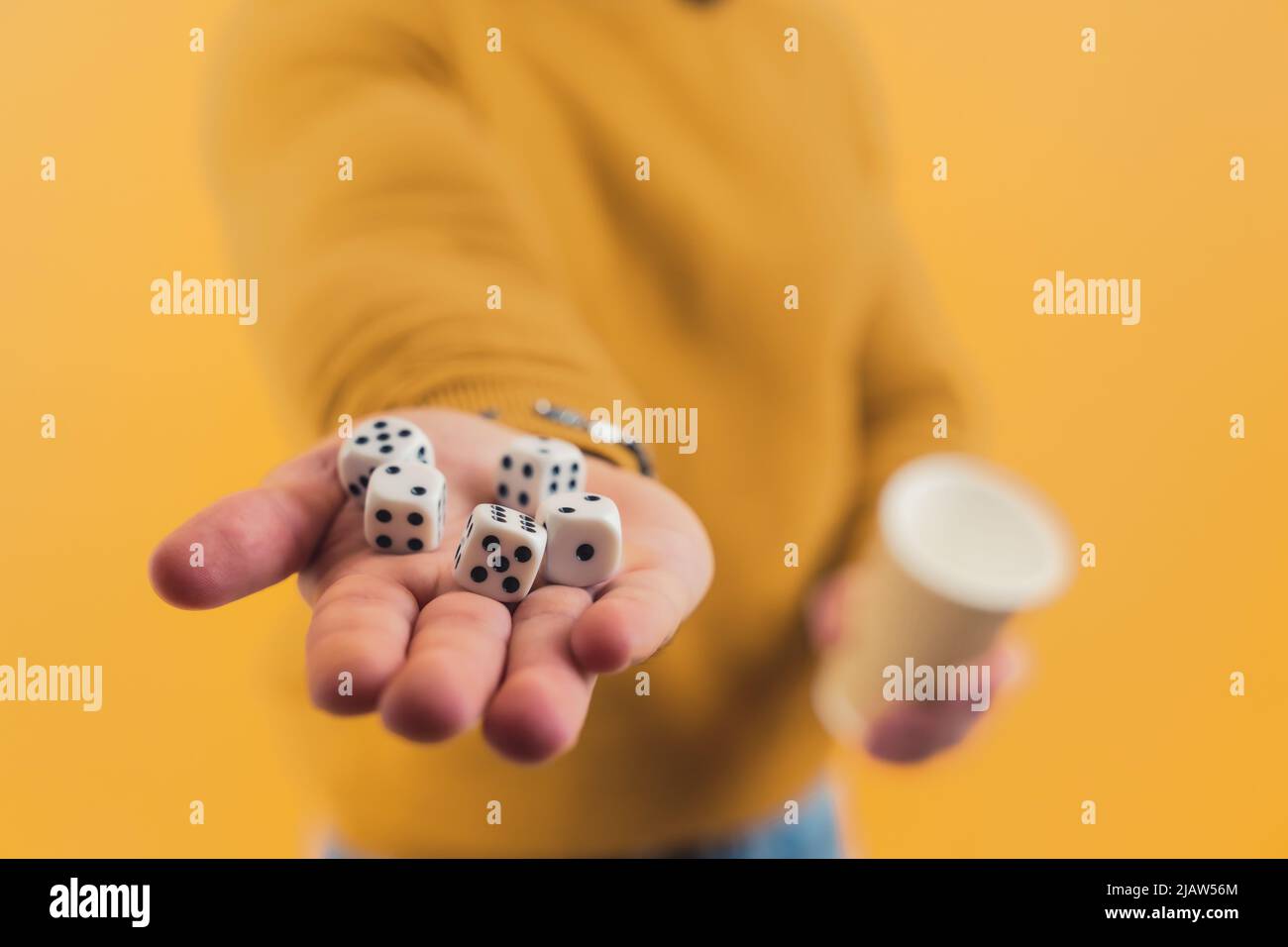 Giovane uomo europeo che mostra i dadi in mano e una tazza in un altro sfondo giallo copia spazio studio girato . Foto di alta qualità Foto Stock