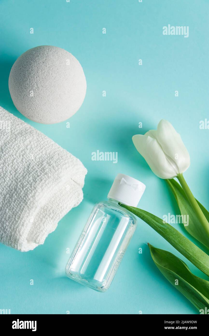 Prodotti per la cura della pelle su sfondo blu. Cosmetici naturali e tulipani bianchi. Posiziona per il testo. Foto Stock