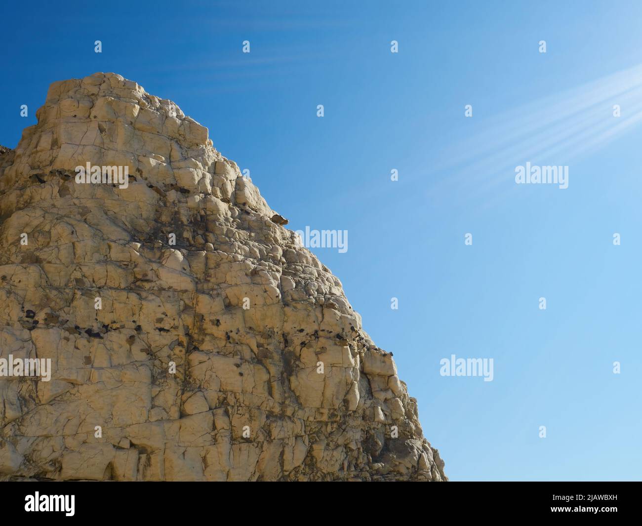 Pulito e semplice, il bordo di una roccia di gesso che si aggettano fuori dalle scogliere a Seaford contro un cielo blu luminoso, tagliato da raggi del sole taglienti. Foto Stock