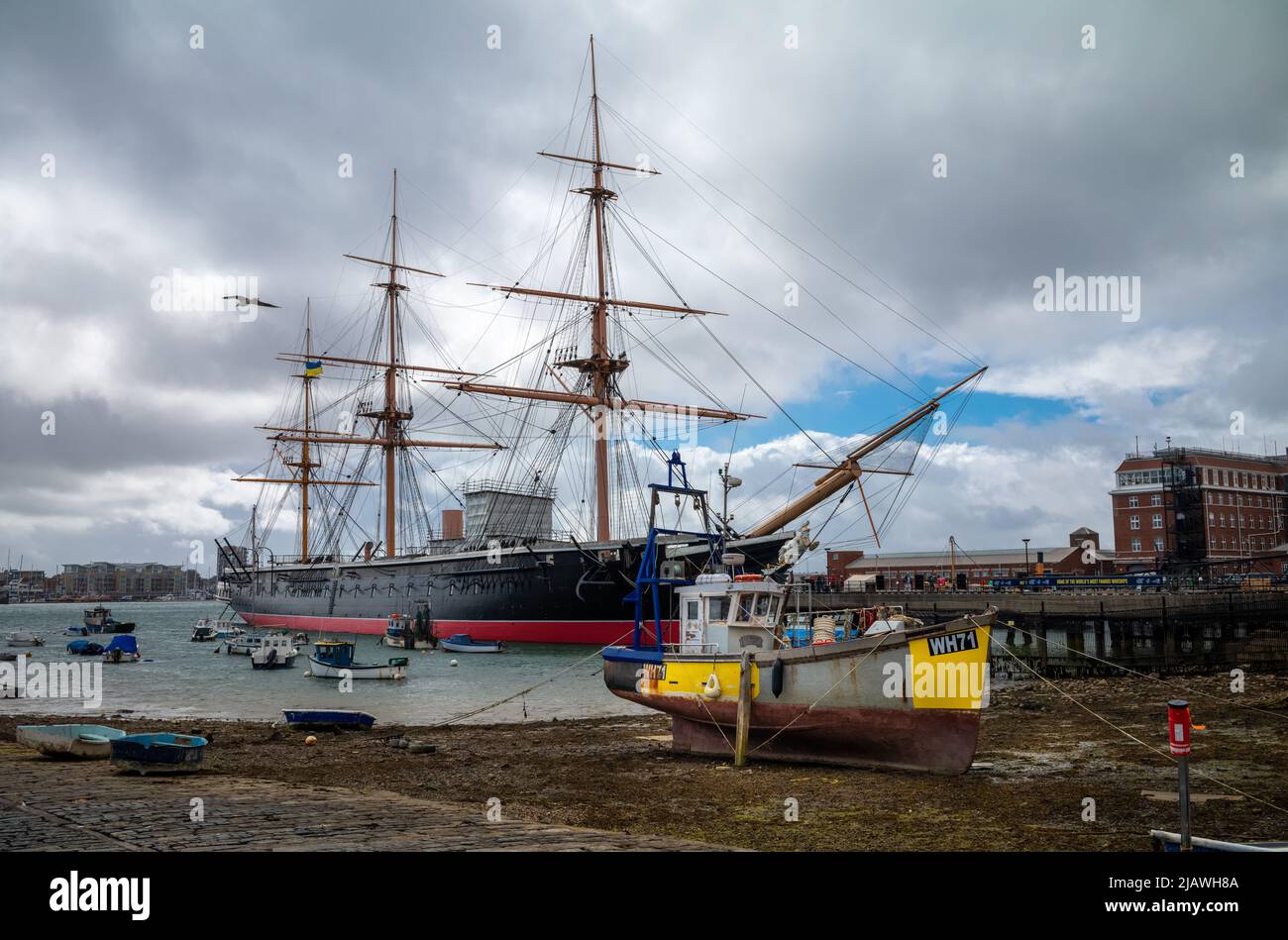 Una barca da pesca abbandonata chiamata la Serime in bassa marea di fronte alla storica nave da guerra HMS Warrior a Portsmouth, Regno Unito Foto Stock