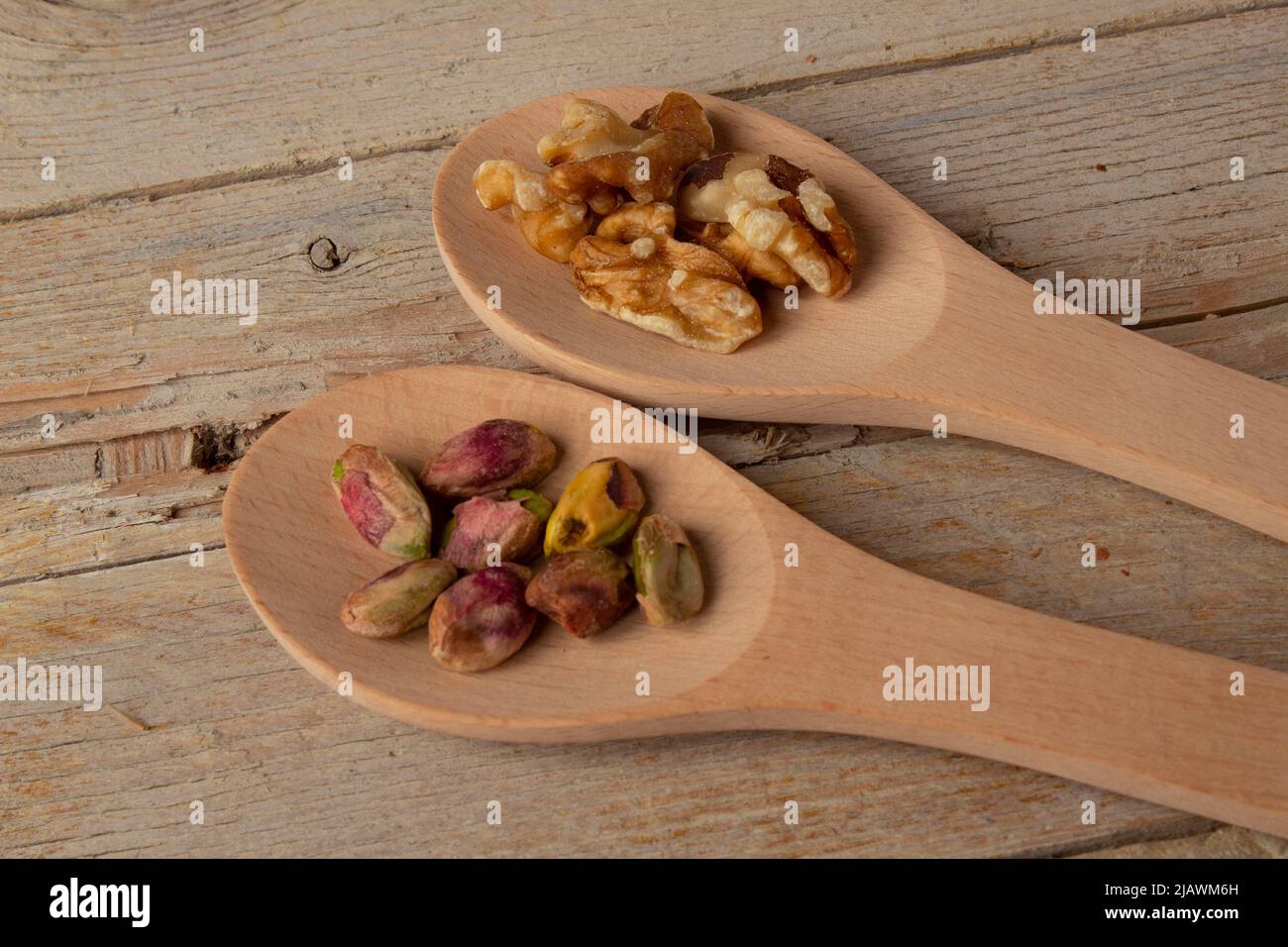 Fotografia di alcuni cucchiai di legno con noci e pistacchi. Foto Stock