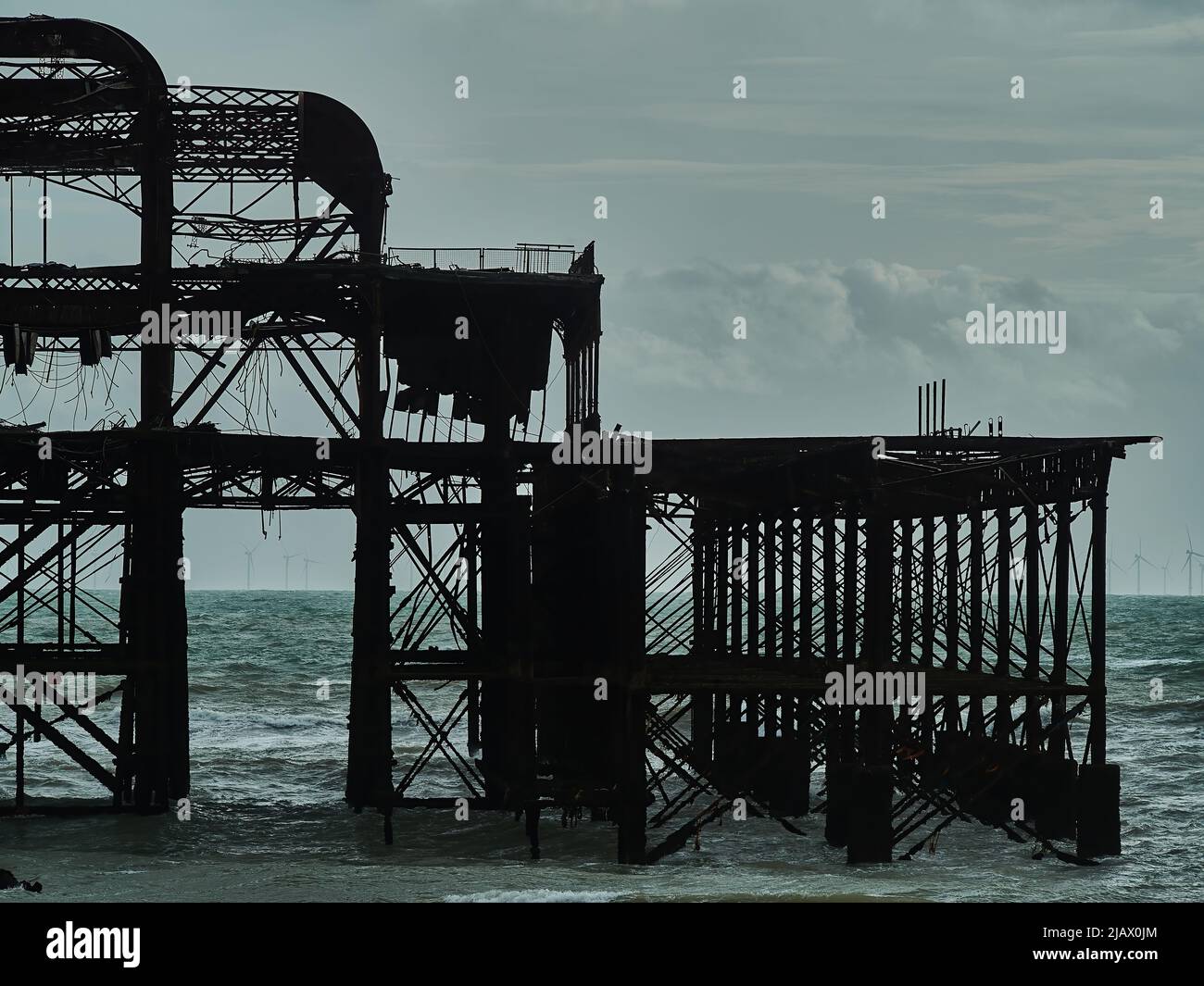 I resti scheletrici del rovinato West Pier al largo di Brighton Beach, intricati lavori di metallo che si profilano con il bagliore di un suggestivo paesaggio all'orizzonte Foto Stock