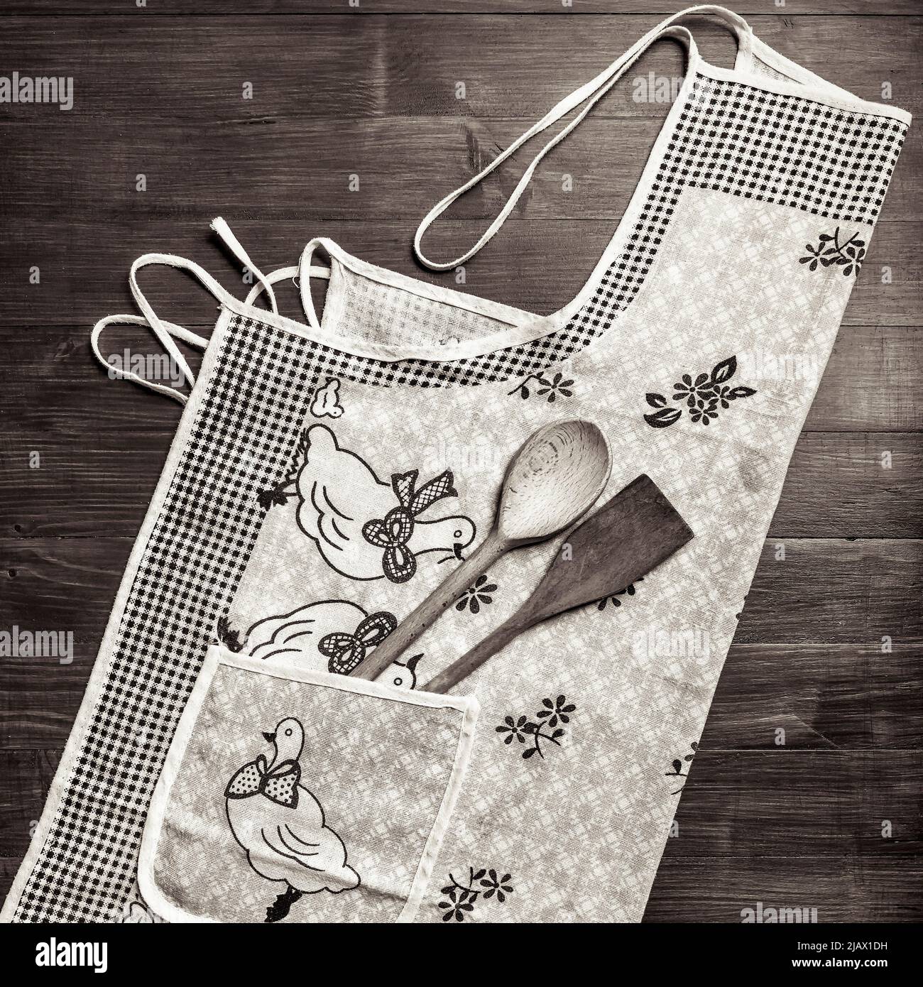 Un grembiule da cucina con utensili in legno in una tasca su sfondo di legno Foto Stock