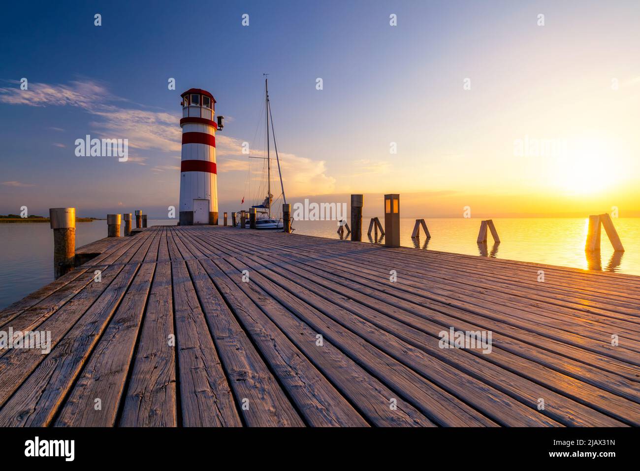 Faro di lago di Neusiedl, Podersdorf am See, Burgenland, Austria. Faro al tramonto in Austria. Il molo di legno con il faro in Podersdorf sul lak Foto Stock
