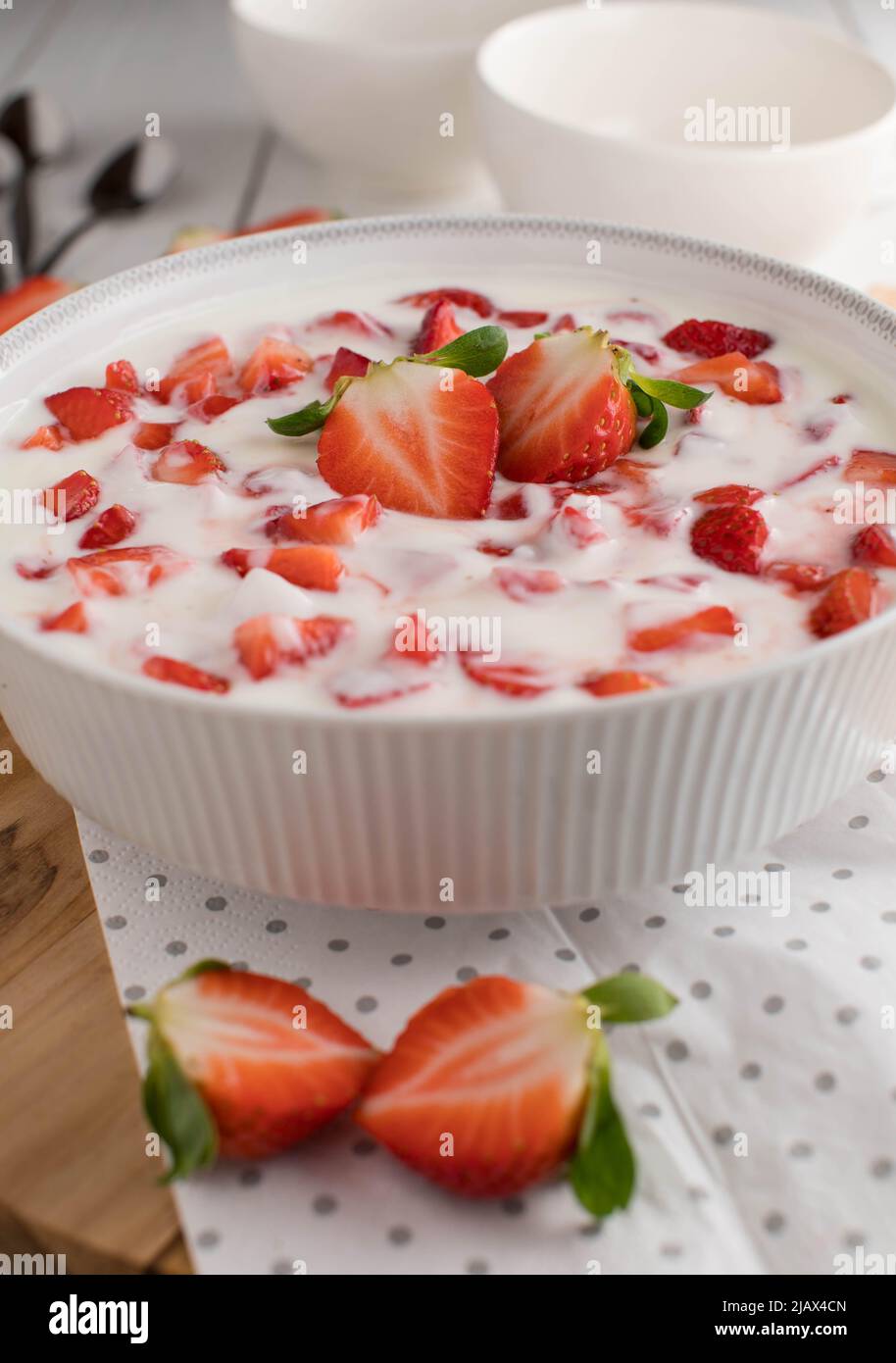 Dolce sano con fragole fresche tritate e yogurt biologico in un recipiente bianco sul tavolo da cucina Foto Stock